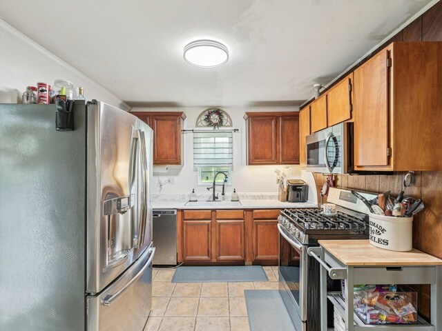kitchen with light tile patterned floors, a sink, stainless steel appliances, and light countertops