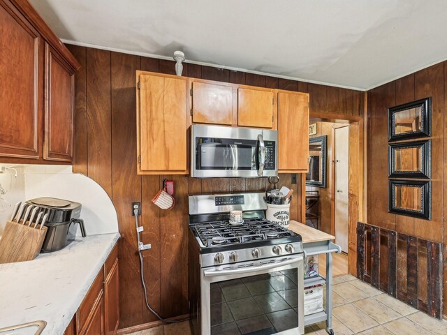 kitchen with wooden walls, appliances with stainless steel finishes, and light countertops