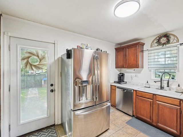 kitchen with light tile patterned floors, stainless steel appliances, a wealth of natural light, light countertops, and a sink