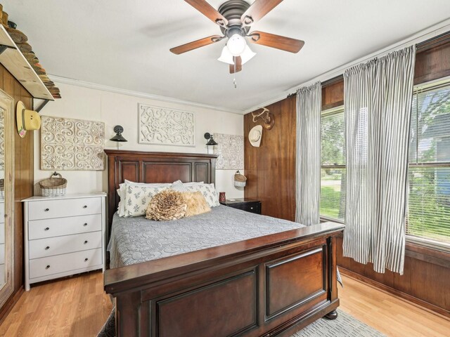 bedroom with crown molding, a ceiling fan, multiple windows, and light wood-style floors