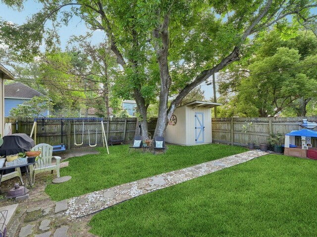 view of yard featuring an outdoor structure, a storage unit, and a fenced backyard