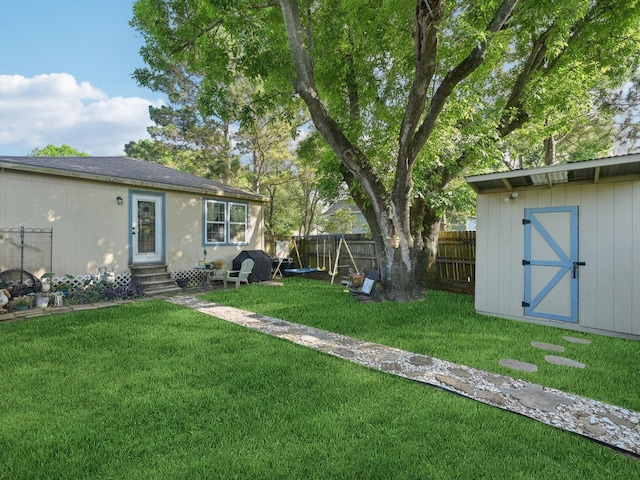 view of yard featuring a storage shed, entry steps, fence private yard, and an outbuilding