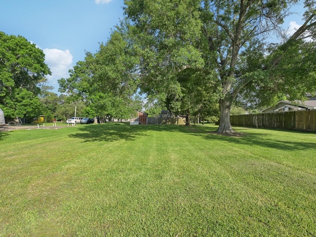 view of yard with fence, a storage unit, and an outbuilding