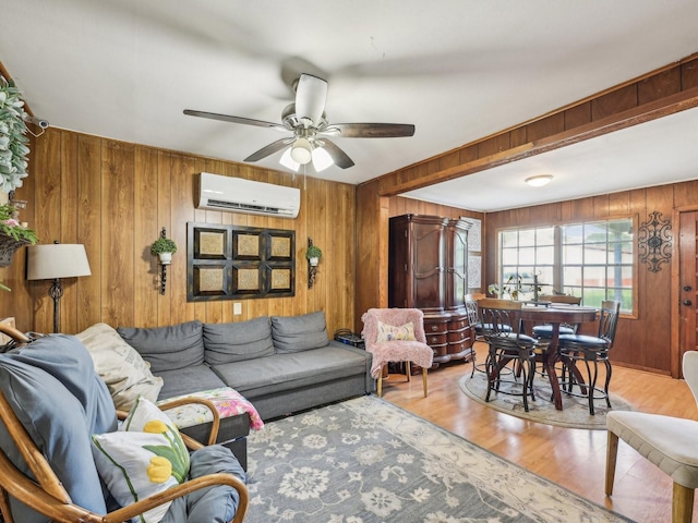 living room with wooden walls, an AC wall unit, ceiling fan, and wood finished floors