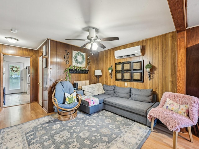 living room featuring a wall mounted air conditioner, wooden walls, ceiling fan, and wood finished floors