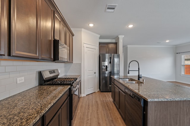 kitchen featuring appliances with stainless steel finishes, a sink, light wood-style floors, visible vents, and ornamental molding