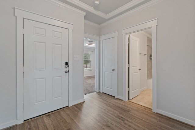 foyer entrance with crown molding, baseboards, and wood finished floors