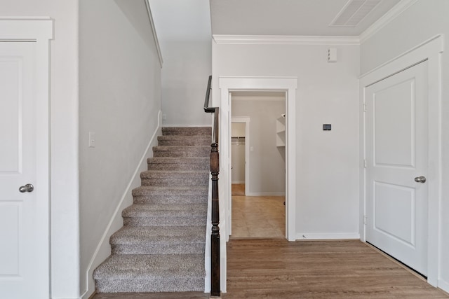 stairway featuring visible vents, ornamental molding, baseboards, and wood finished floors