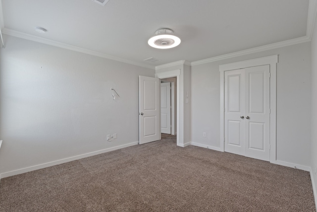 unfurnished bedroom featuring baseboards, ornamental molding, carpet, and a closet