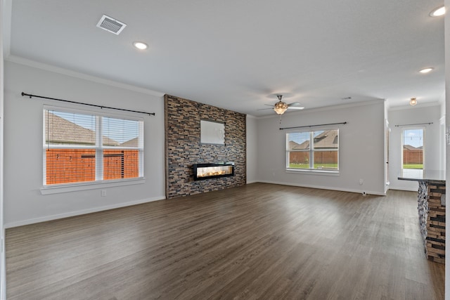 unfurnished living room featuring crown molding, visible vents, a stone fireplace, dark wood-type flooring, and a ceiling fan