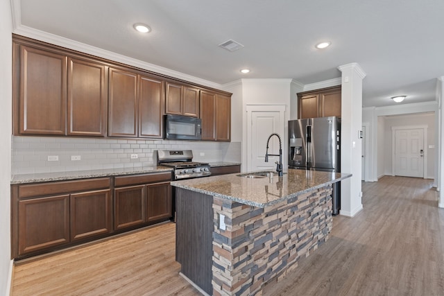 kitchen with visible vents, stone countertops, a sink, light wood-style flooring, and appliances with stainless steel finishes