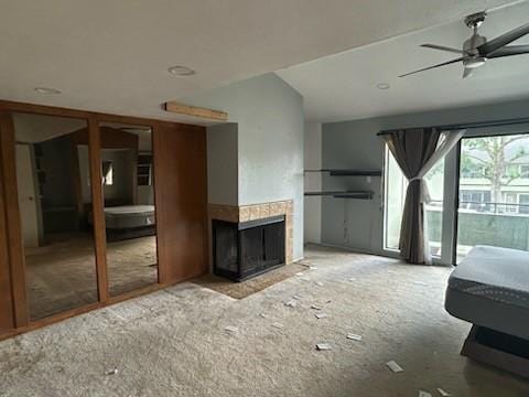 living area with a tile fireplace and a ceiling fan