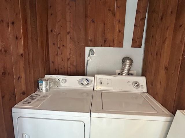washroom with wooden walls, separate washer and dryer, and laundry area