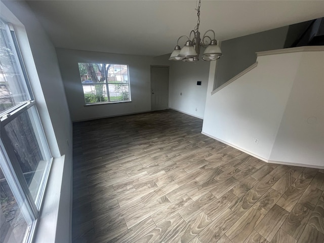 unfurnished dining area with wood finished floors and a notable chandelier