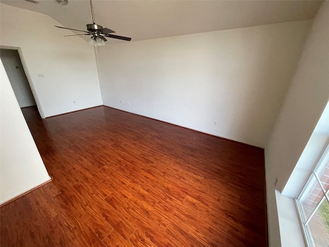 empty room with dark wood-style flooring, a ceiling fan, and vaulted ceiling