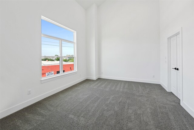 spare room with dark colored carpet and baseboards