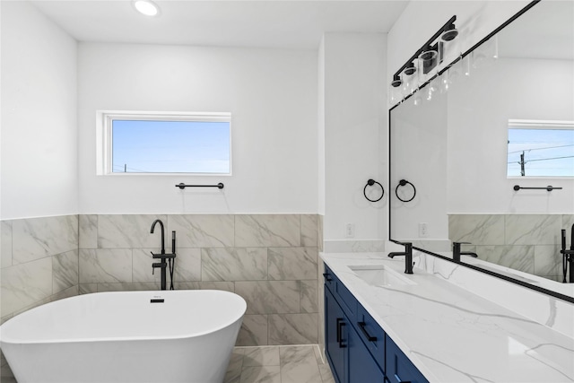 full bath featuring tile walls, a freestanding bath, vanity, and plenty of natural light