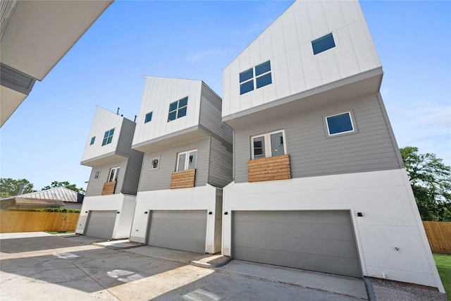 contemporary home with board and batten siding, stucco siding, fence, a garage, and driveway