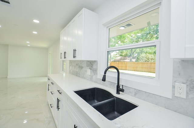 6107 Kuldell Dr, Houston, TX 77074 - kitchen with recessed lighting, light stone counters, tasteful backsplash, white cabinetry, and light marble finish floors