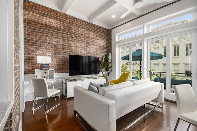 living room with beam ceiling, dark wood-type flooring, ceiling fan, and brick wall