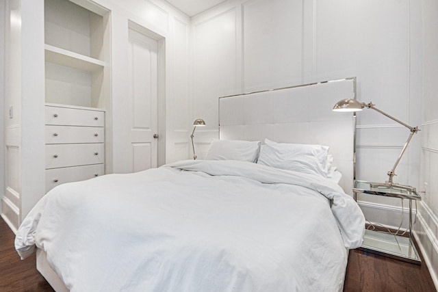 bedroom featuring a decorative wall and dark wood finished floors