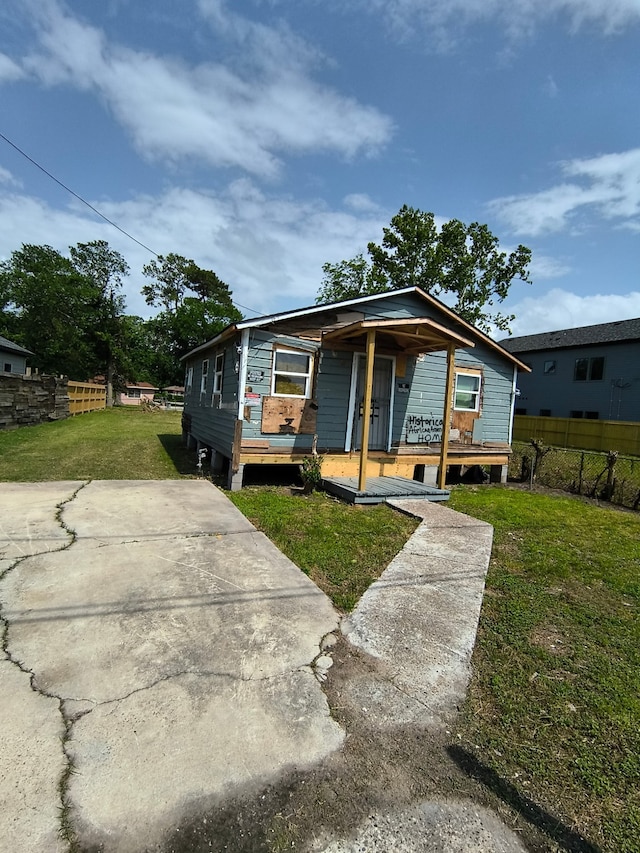 bungalow-style home featuring fence, covered porch, and a front yard
