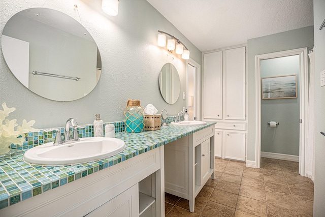 bathroom featuring baseboards, backsplash, double vanity, and a sink