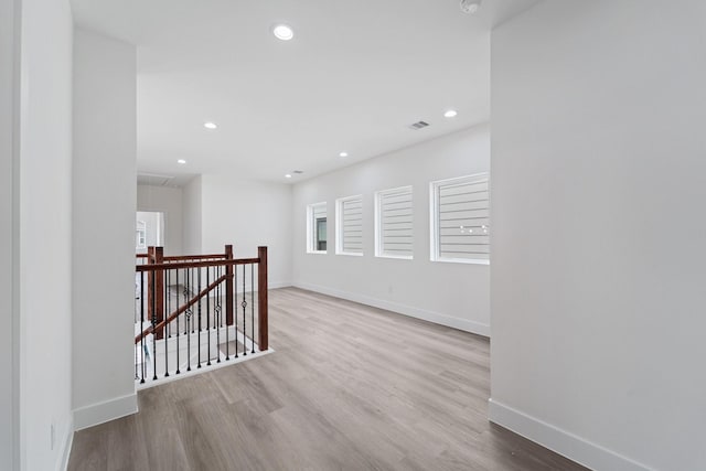 unfurnished room with wood finished floors, recessed lighting, visible vents, and baseboards