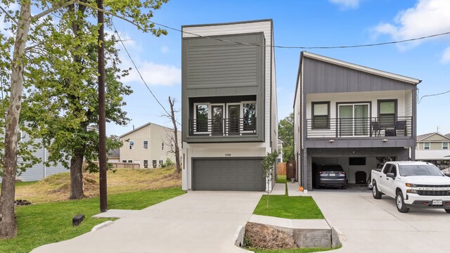 modern home featuring a front yard, driveway, an attached garage, and board and batten siding