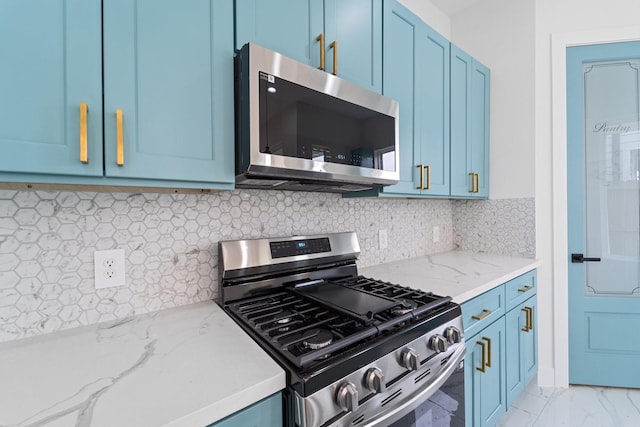 kitchen with light stone countertops, decorative backsplash, stainless steel appliances, blue cabinetry, and marble finish floor