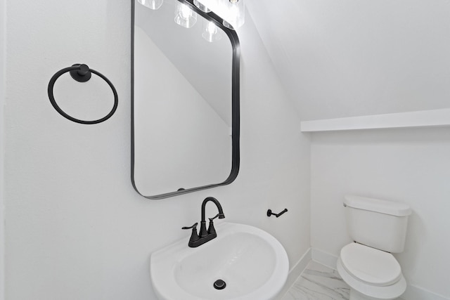 bathroom with toilet, baseboards, marble finish floor, and a sink