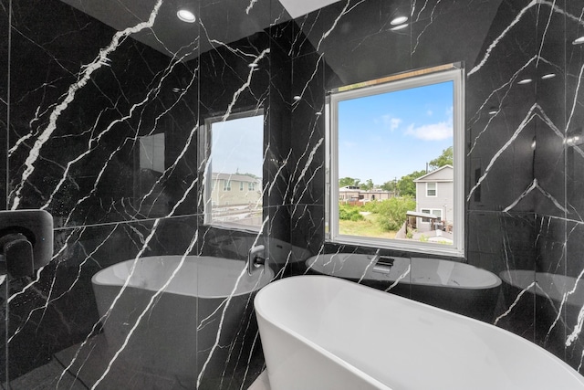 bathroom featuring a freestanding bath and tile walls
