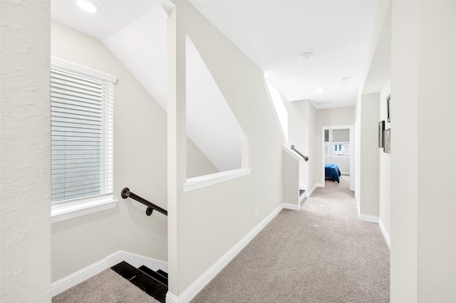 corridor with an upstairs landing, carpet, and baseboards