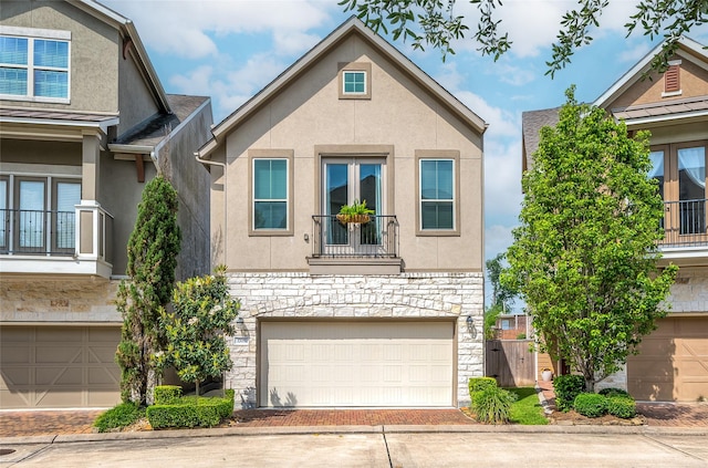 view of front of home featuring stucco siding, decorative driveway, stone siding, a balcony, and an attached garage