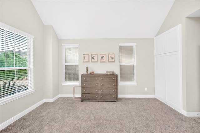 carpeted bedroom with lofted ceiling and baseboards