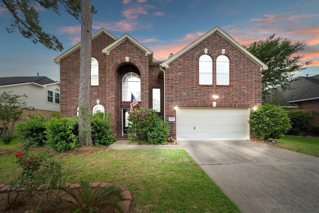traditional home with brick siding, a garage, a front yard, and concrete driveway