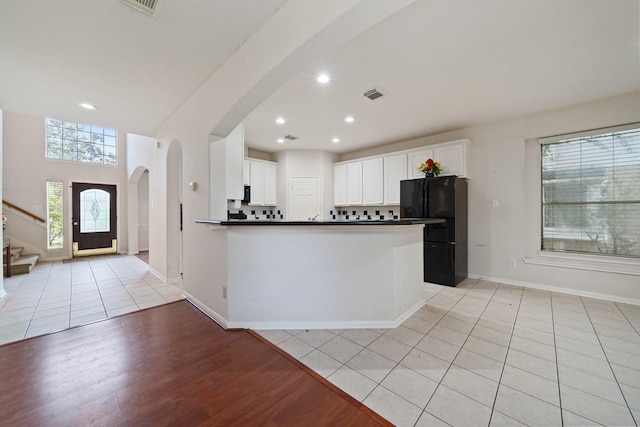 kitchen featuring visible vents, freestanding refrigerator, dark countertops, open floor plan, and arched walkways
