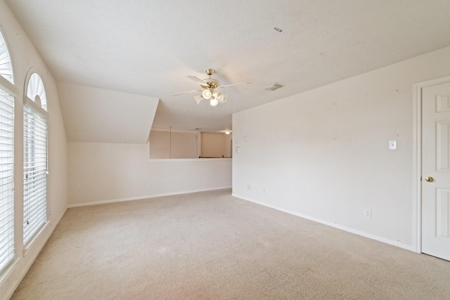 additional living space featuring light colored carpet, a ceiling fan, baseboards, and visible vents