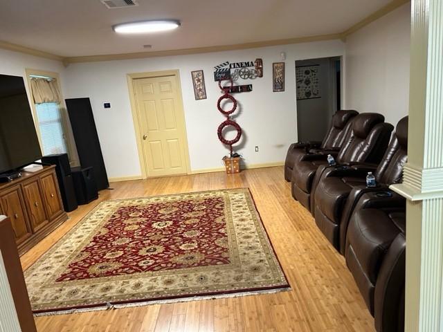 living room featuring baseboards, visible vents, wood finished floors, and crown molding
