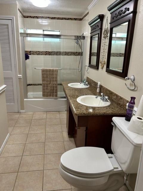 bathroom featuring toilet, a sink, ornamental molding, and tile patterned floors