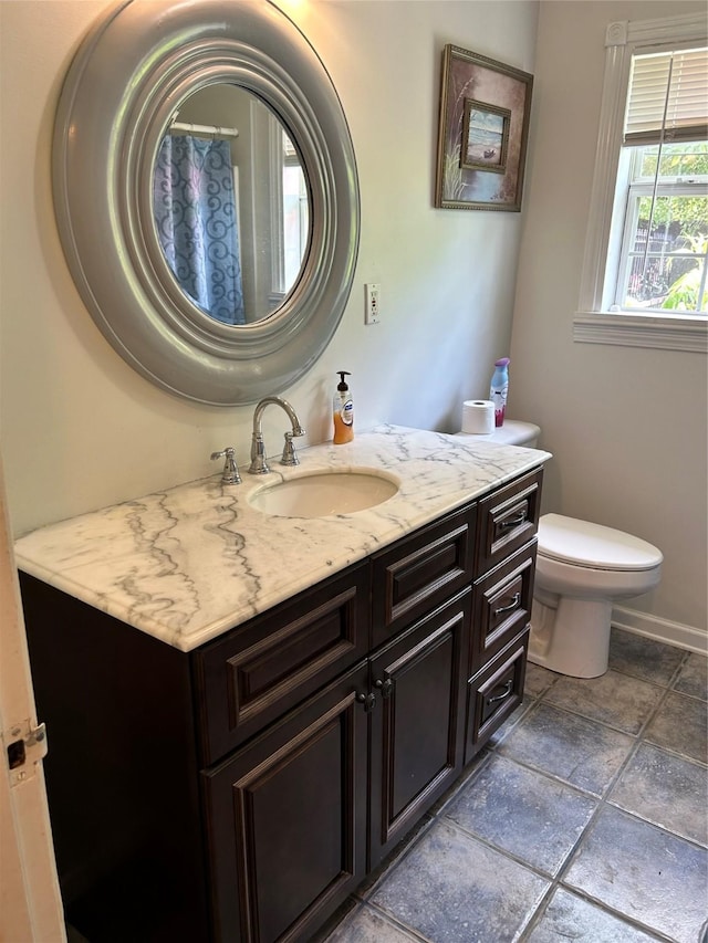 bathroom featuring toilet, vanity, and baseboards