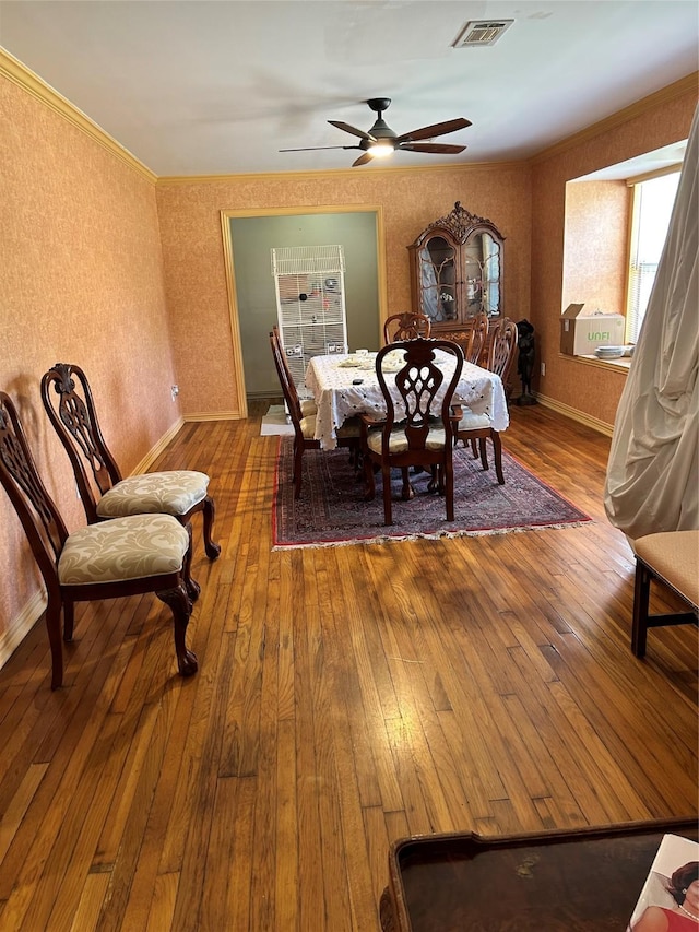 dining room with visible vents, ornamental molding, ceiling fan, and wood-type flooring