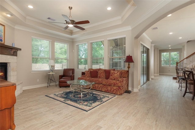 living area featuring a fireplace, baseboards, light wood-style floors, arched walkways, and a ceiling fan