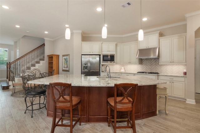 4044 Windsor Chase Dr, Spring, TX 77386 - kitchen with stainless steel appliances, a sink, under cabinet range hood, decorative backsplash, and light wood-style floors