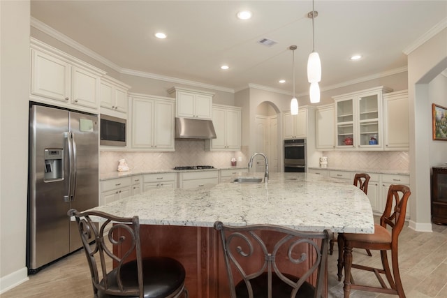kitchen featuring visible vents, appliances with stainless steel finishes, a sink, light wood-style floors, and under cabinet range hood