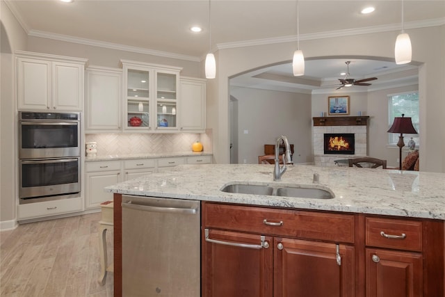 kitchen featuring ceiling fan, a sink, arched walkways, stainless steel appliances, and backsplash