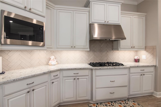 kitchen with gas cooktop, white cabinets, stainless steel microwave, and under cabinet range hood