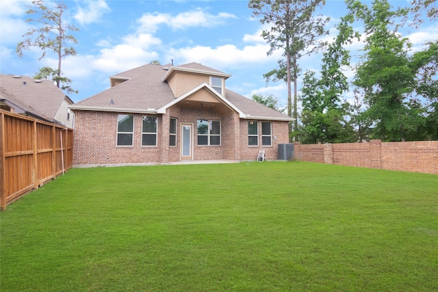 back of property featuring a lawn, brick siding, central AC unit, and a fenced backyard
