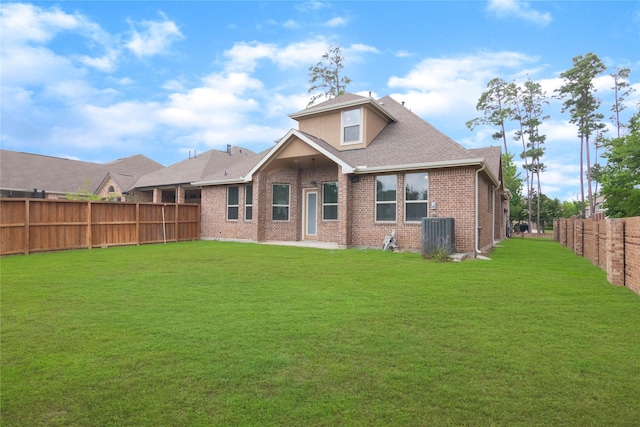 rear view of property with a fenced backyard, a yard, roof with shingles, and brick siding
