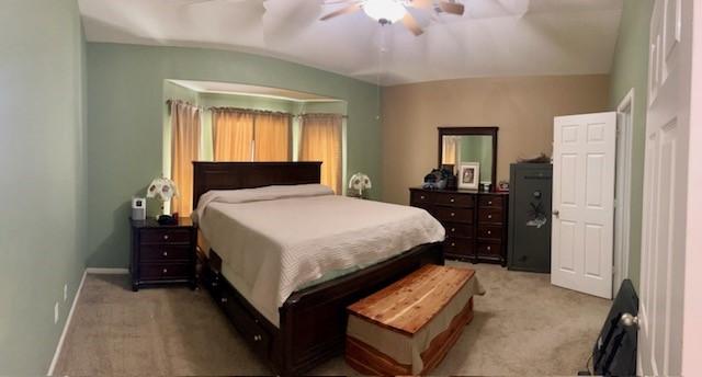 bedroom with ceiling fan, light carpet, and baseboards